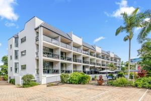 una vista exterior de un edificio blanco con una palmera en Shelly Bay Resort, en Hervey Bay
