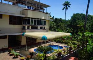 a building with a large umbrella in front of a pool at Parvathy Serenity In Varkala in Attingal