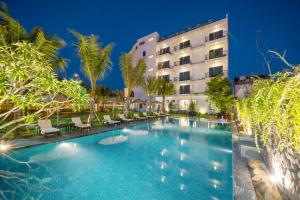 a pool in front of a hotel at night at Athenia Hoi An Boutique Hotel & Spa in Hoi An