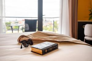 a book and pair of glasses on a bed at Athenia Hoi An Boutique Hotel & Spa in Hoi An