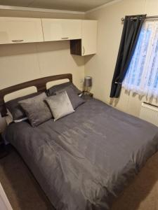 a bedroom with a large bed with gray sheets and pillows at 163 Holiday Resort Unity Brean sands Pet friendly in Berrow