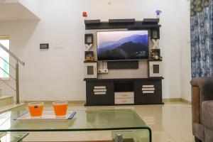 ロナバラにあるshubh yellow villa 3BHKのテレビとガラスのテーブルに置かれた2つの飲み物があるリビングルーム