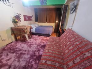 Un dormitorio con una cama y un sofá con una alfombra morada. en IG Suites & Apartment, en Cusco
