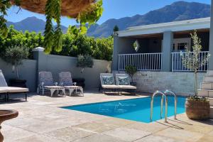 Un patio con piscina y sillas y una casa. en C'est la Vie 1, en Franschhoek