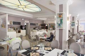 Hotel San Salvador في بيلاريا-إيجيا مارينا: مطعم بطاولات وكراسي وساعة كبيرة