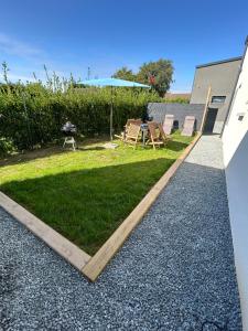 un patio trasero con parrilla, sillas y césped en Gîte Anna - Maison à proximité de la mer, en Saint-Jean-de-la-Rivière 4 fotos más
