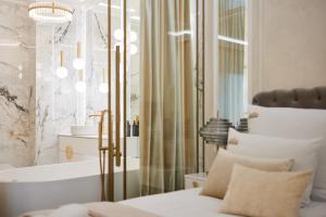 a bathroom with a tub and a bed and a chandelier at Jacuzzi Mirror Suite by Downtown Apartments in Gdańsk
