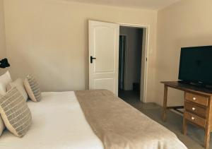 Un dormitorio con una cama blanca y un televisor. en Molenhof, en Somerset East