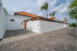 a white wall with a fence next to a driveway at Special Offer! Elegant 2-Bedroom Villa with Large Pool in Canggu! in Canggu