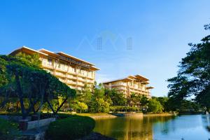 a large building next to a river with trees at PICO DE LORO Pool Accessible CAROLA 2 Bedroom Units by SEE Condominiums in Nasugbu