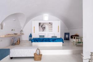 Un dormitorio con una cama azul en una habitación blanca. en Art Canava Luxury Villas, en Fira
