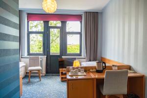 a hotel room with a bed and a desk and two windows at Hotel Haus Martens in Hannover