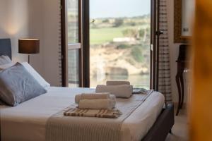 a bed with two towels on it with a window at Apartment baia Minareto in Plemmirio