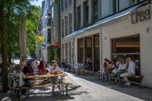 un gruppo di persone seduti ai tavoli su un marciapiede di Antwerp For Two B&B ad Anversa