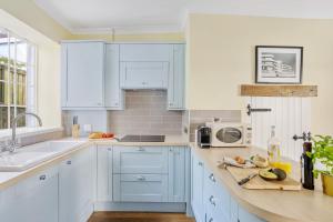 een witte keuken met blauwe kasten en een wastafel bij Cherub Cottage located in the centre of Historic Dartmouth in Dartmouth