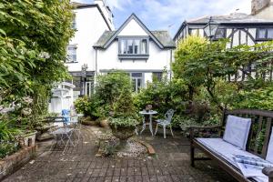 een tuin met een bank en een tafel voor een huis bij Cherub Cottage located in the centre of Historic Dartmouth in Dartmouth