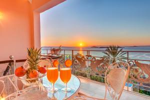 Un balcón con una mesa con vasos de zumo de naranja. en Veranda Syros House, en Ermoupoli