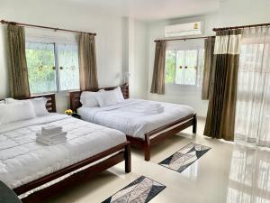 a bedroom with two beds and two windows at BAAN OZONE HY2 in Hat Yai