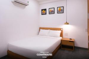 a bedroom with a white bed and a night stand at Coast House Boutique Hotel in Nha Trang