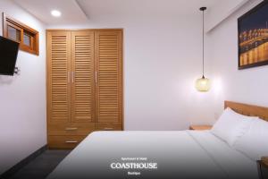 a bedroom with a bed and a wooden closet at Coast House Boutique Hotel in Nha Trang