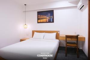 a room with a bed and a desk and a bed and a table at Coast House Boutique Hotel in Nha Trang