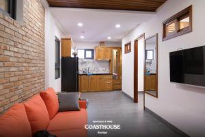 a living room with an orange couch and a kitchen at Coast House Boutique Hotel in Nha Trang