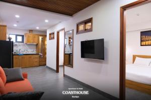a room with a bed and a television on a wall at Coast House Boutique Hotel in Nha Trang