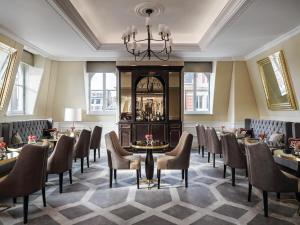 a dining room with tables and chairs and a chandelier at The Langham London in London