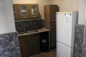 a small kitchen with a refrigerator and a sink at Tucked-Away 1&2 Bedroom Houses in Nelspruit