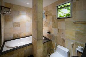 a bathroom with a tub and a toilet and a window at Benzen Boutique Villa Private Pool By Da Nang Beach 8Pax in Da Nang