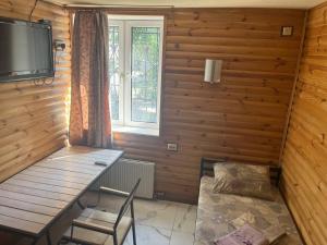 a room with a wooden wall with a table and a television at PitStop Motel in Kamianske