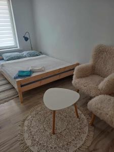 a bedroom with a bed and a stool and a chair at Apartament w Piszu in Pisz