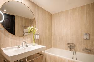 a bathroom with a sink and a tub and a mirror at Hotel Barsey by Warwick in Brussels