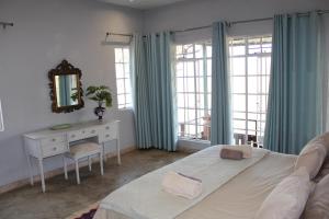 a bedroom with a bed and a desk and windows at Tucked-Away 1&2 Bedroom Houses in Nelspruit