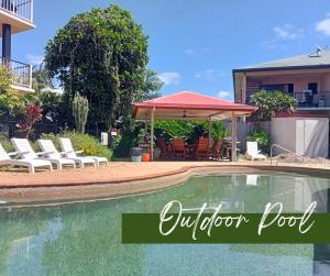 a swimming pool with chairs and a gazebo at Cairns Chic Suite - Motel Room A in Woree