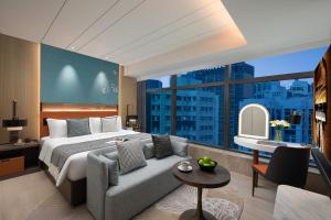 sypialnia z łóżkiem, kanapą i dużym oknem w obiekcie Ascott North Point Hong Kong w Hongkongu