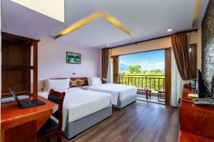 a bedroom with a bed and a desk and a television at Lisha Garden Resort Hotel in Vang Vieng