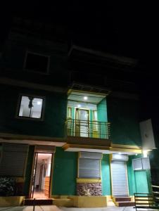 a green building with a balcony at night at Princesa el gallo inn in Puerto Princesa City