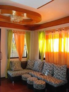 a living room with a couch in front of curtains at Princesa el gallo inn in Puerto Princesa City