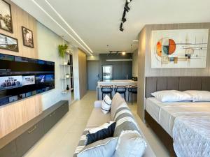 a room with two beds and a couch and a tv at A Melhor Vista com Academia no Rooftop in Campo Grande