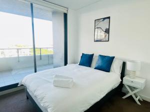 a white bed with blue pillows in a room with a window at Stunning waterfront 3 bedroom condo with Pool, BBQ in Sydney +18 photos
