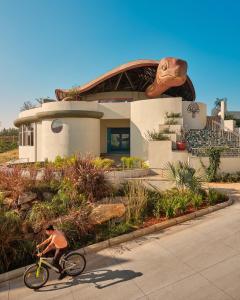a man riding a bike in front of a house at Kshemavana The Wellness Retreat in Bengaluru