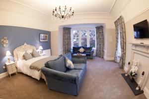 a bedroom with a bed and a chair and a chandelier at Inglewood House and Spa in Alloa