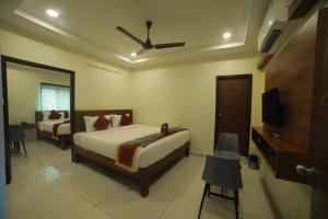 a bedroom with two beds and a flat screen tv at Hotel Roi Inn in Tirupati