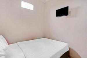 a small white room with a bed and a tv at Kediri Homes Guest House in Kediri