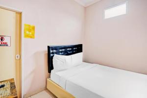 a small room with a white bed in it at Kediri Homes Guest House in Kediri