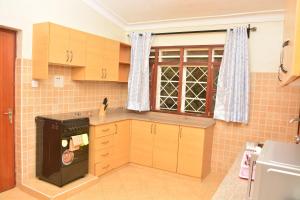 a kitchen with wooden cabinets and a black stove at Kaizen Residences in Entebbe