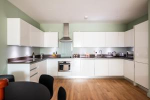 a large kitchen with white cabinets and a table at Native Victoria in London