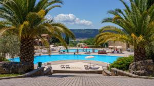 a swimming pool with palm trees in a resort at Residence with swimming pool immersed in the typical Tuscan countryside just 5 minutes from Massa Marittima in Podere Pian Mucini