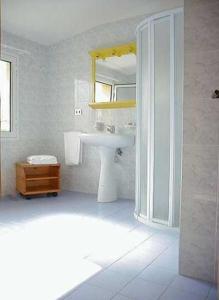 uma casa de banho branca com um lavatório e um espelho em Hotel Garni Tosca em Lido di Jesolo